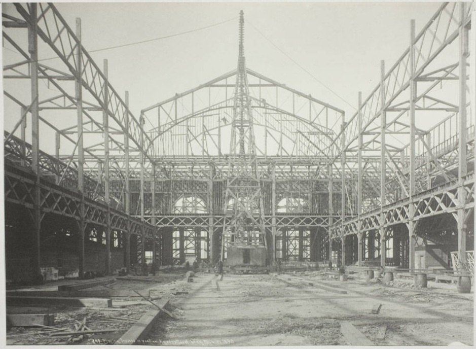 Foto antigua en blanco y negro del interior de un edificio en obras: solo se ve el esqueleto de vigas de hierro y madera, sin paredes