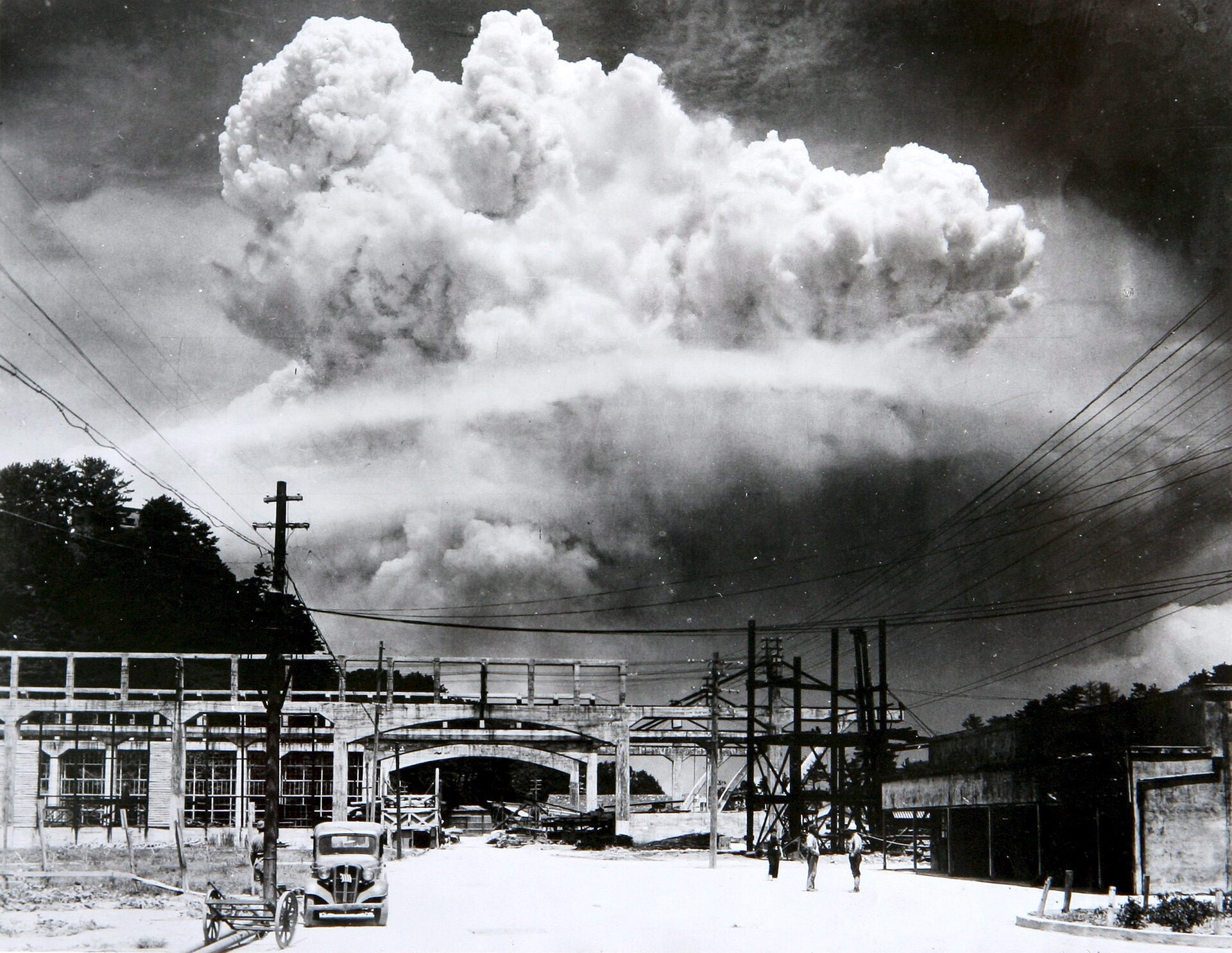 Fotografía en blanco y negro de la nube de la bomba atómica elevándose sobre Nagasaki, vista desde un astillero