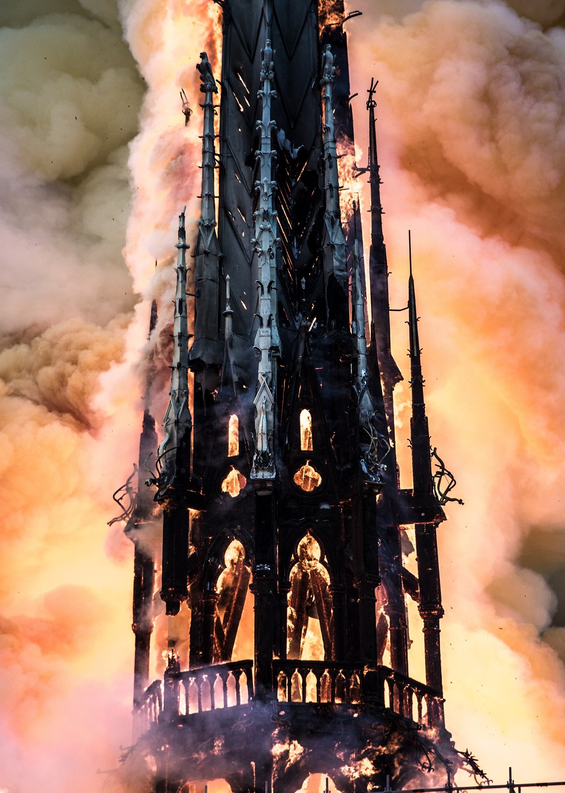 La aguja de piedra y plomo de Notre-Dame envuelta en llamas y humo naranja