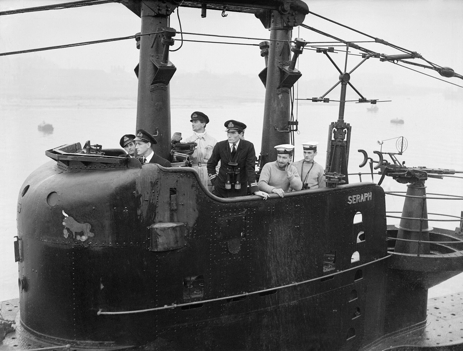 Fotografía antigua en blanco y negro de la torre de un submarino británico con varios marinos de uniforme en lo alto